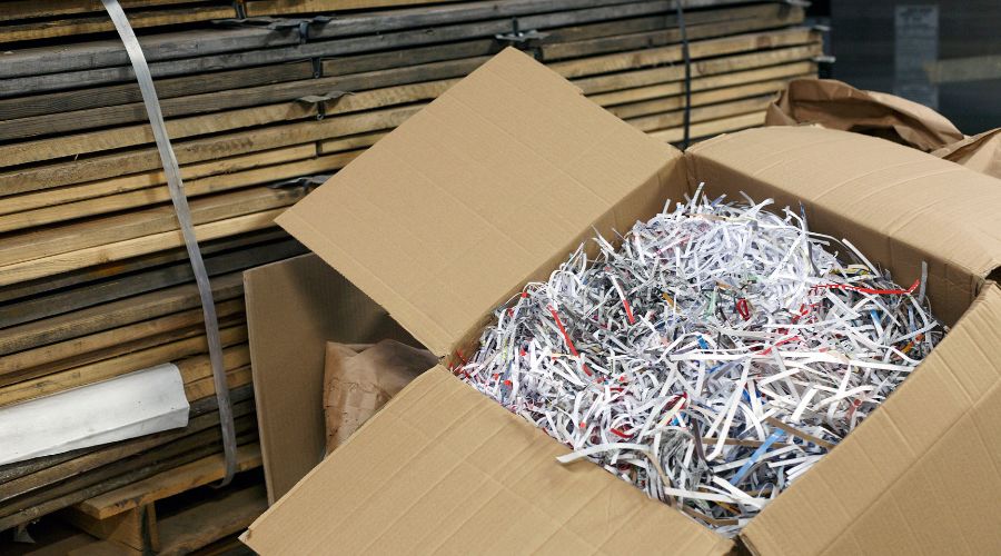 A box filled with shredded paper rests on a table, showcasing a textured, cluttered interior.